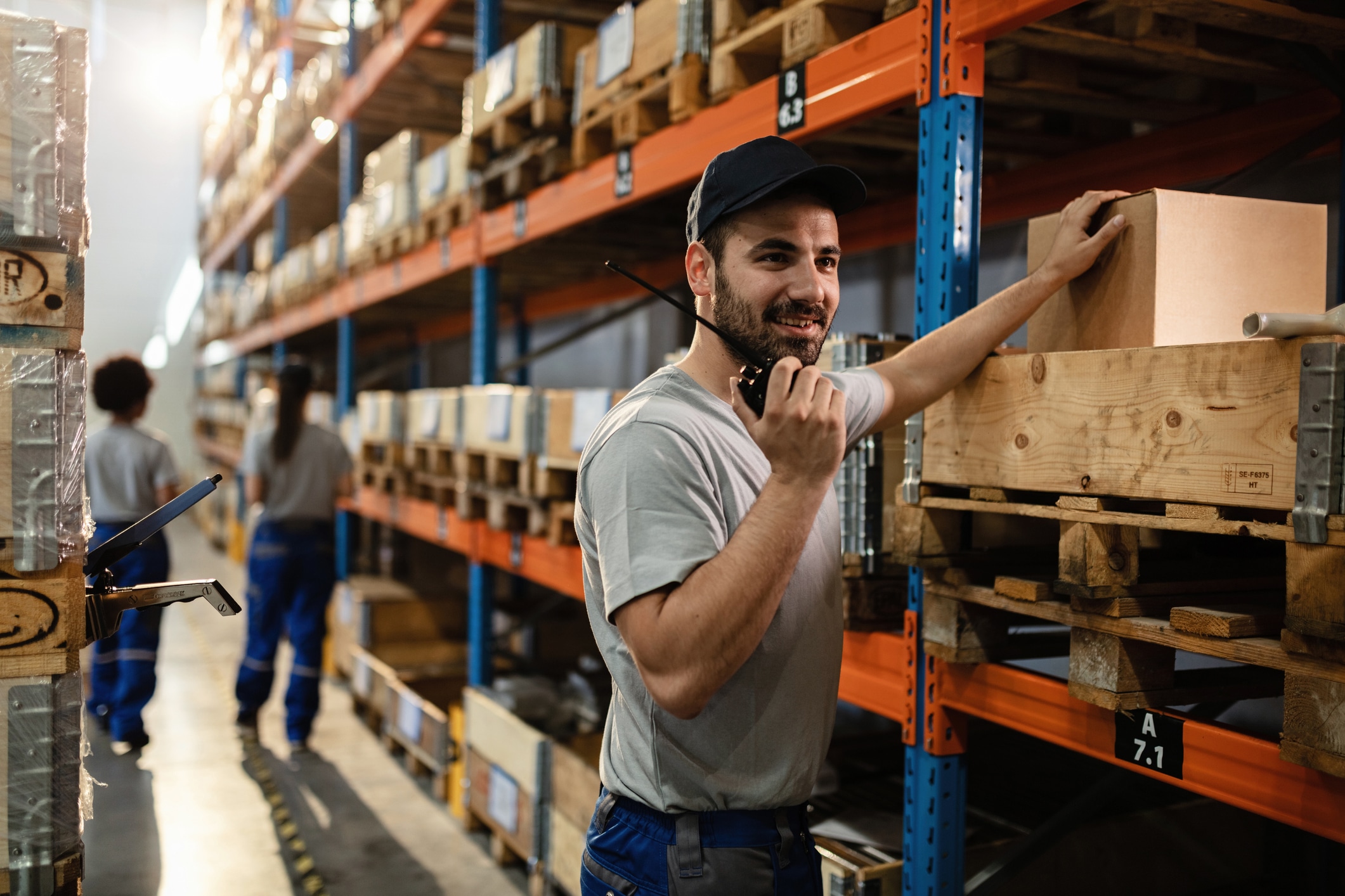General warehouse worker talking on walkie-talkie in a storage room.