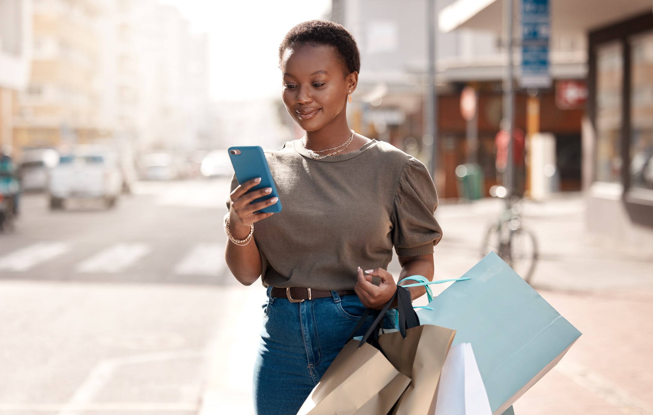 Shot of a young woman using her cellphone outside while shopping in the city