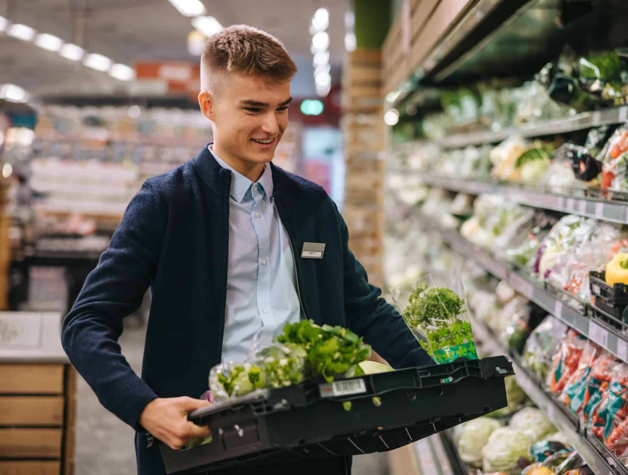 Shop assistant restocking the produce section shelves