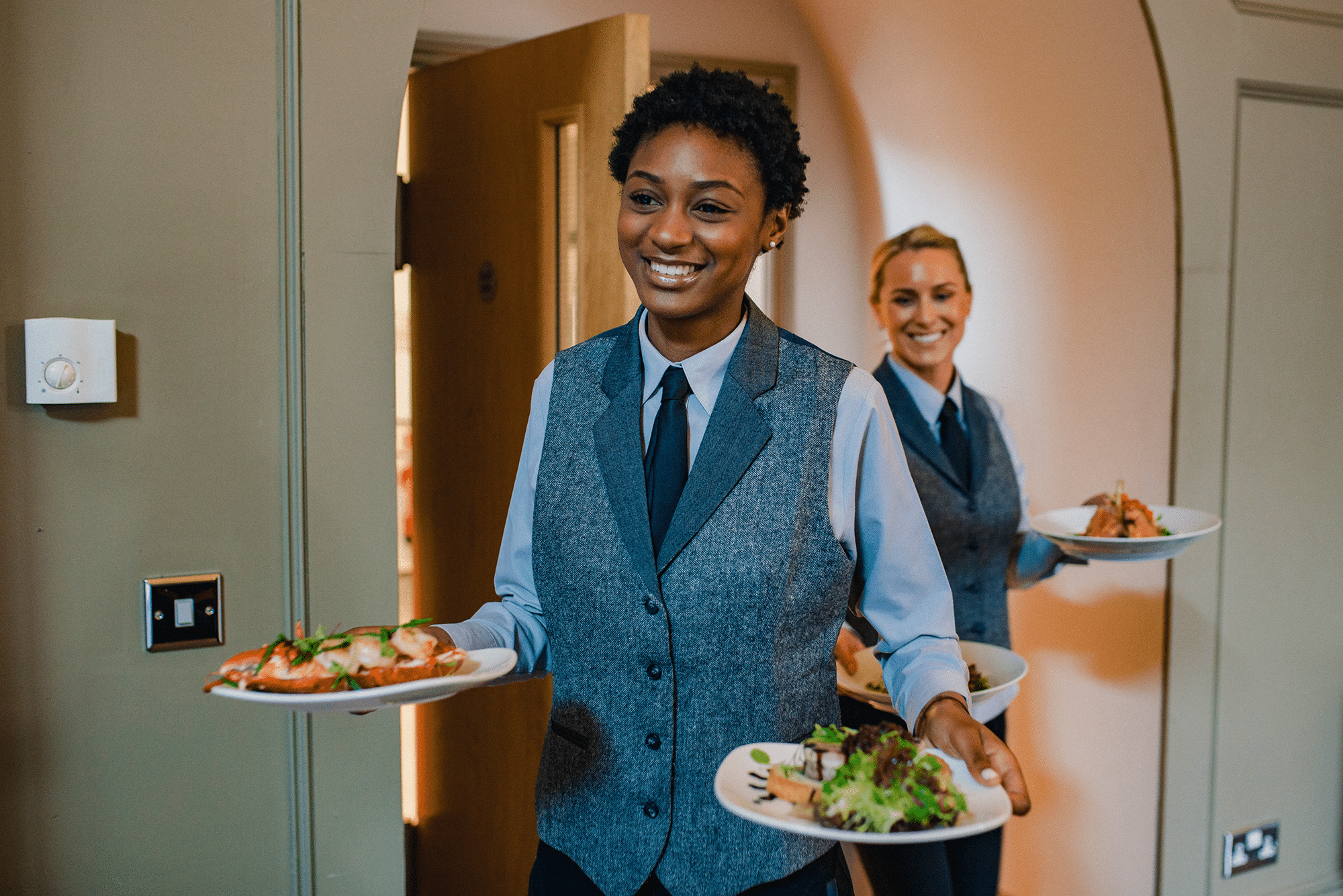 Two women serving plates of food in a restaurant